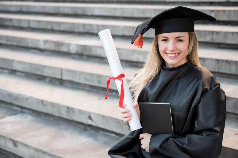 estudiante sonriendo con diploma en la mano